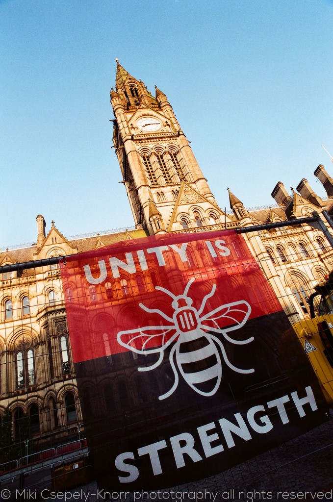 A colour image of bee banner saying 'Unity is Strength' in Albert Square, Manchester in front of the town hall.